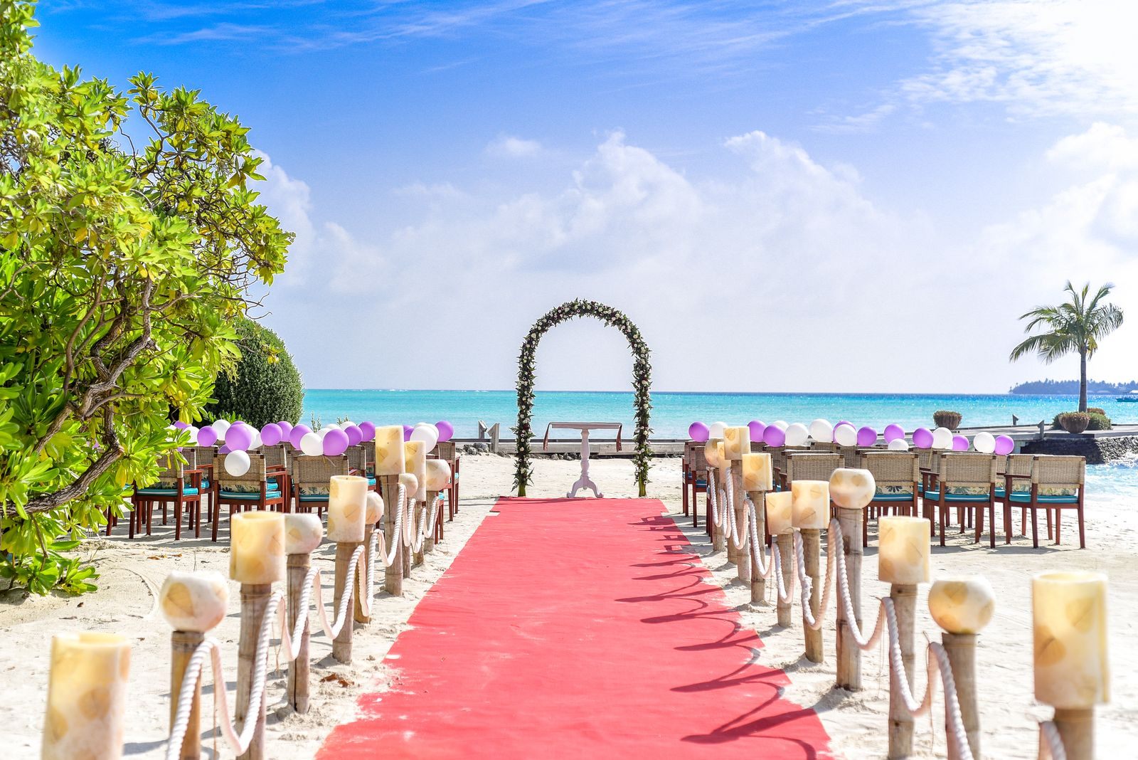 Red-carpet aisle leading to a flower arch on a tropical beach, like the settings on many of the best destination wedding cruises