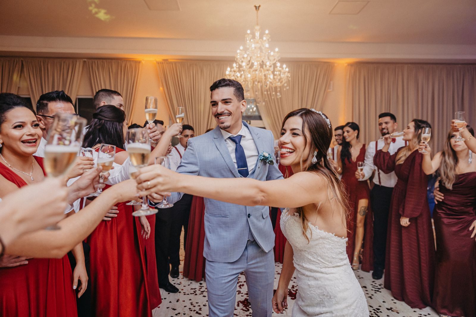 Bride, groom and wedding guests raising champagne glasses together at a reception