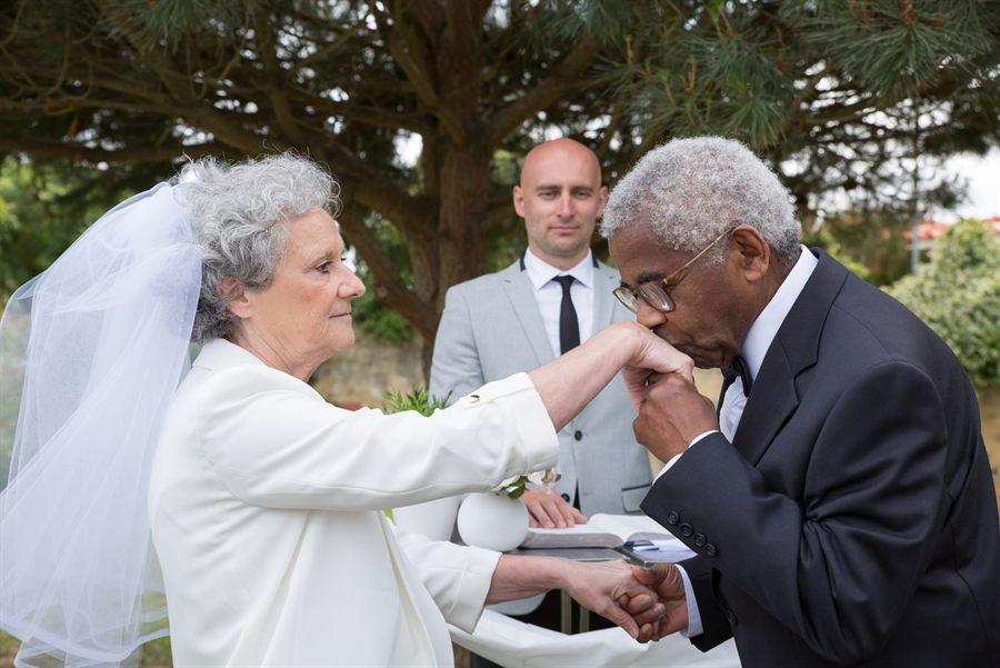 Older bride and groom sharing a tender moment during an outdoor vow ceremony