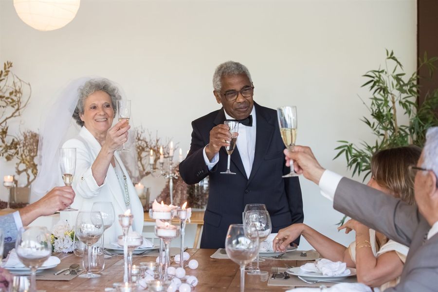 Older couple toasting with champagne at a wedding table with family