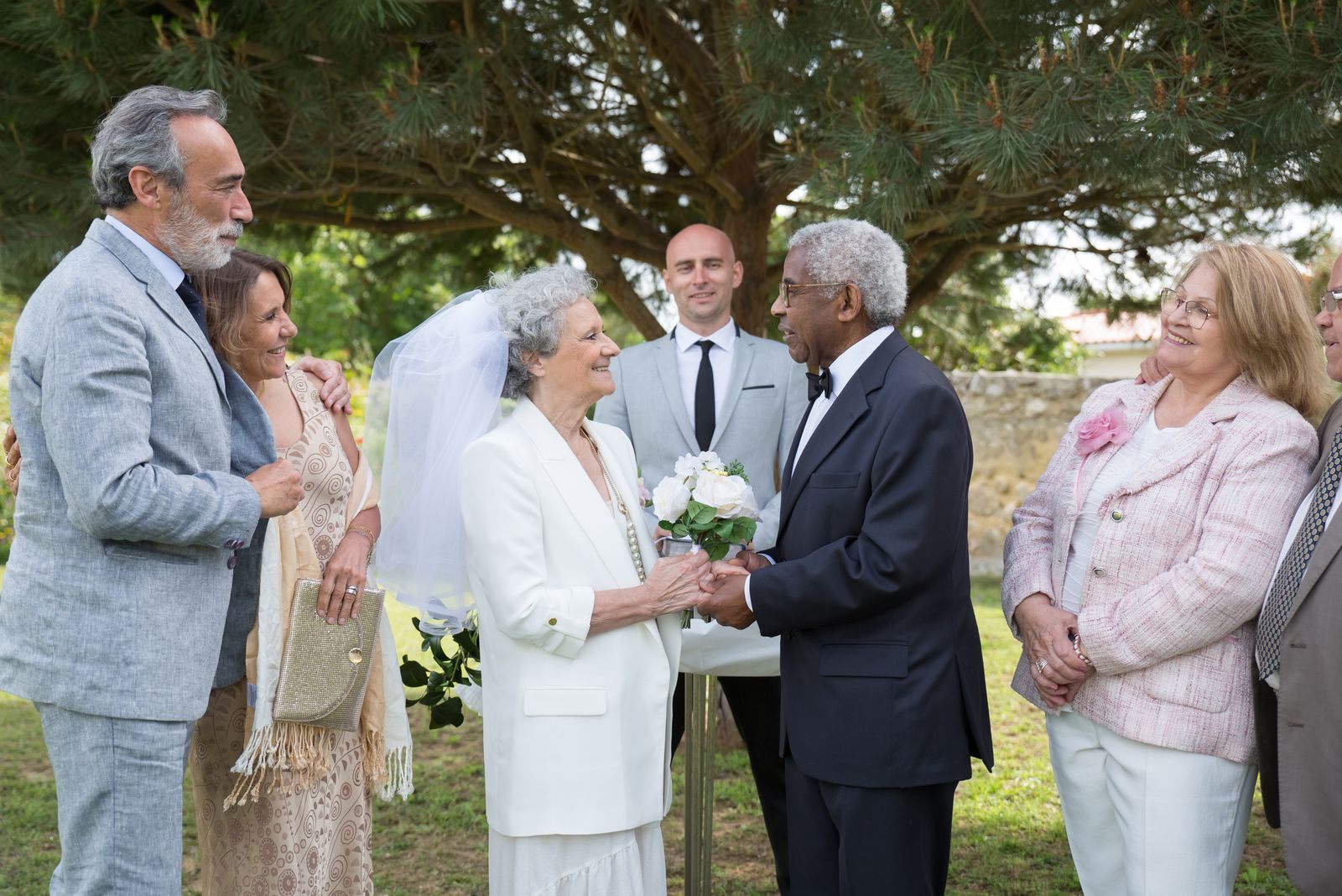 Older couple renewing their vows outdoors surrounded by family and friends, the heart of vow renewal cruise packages